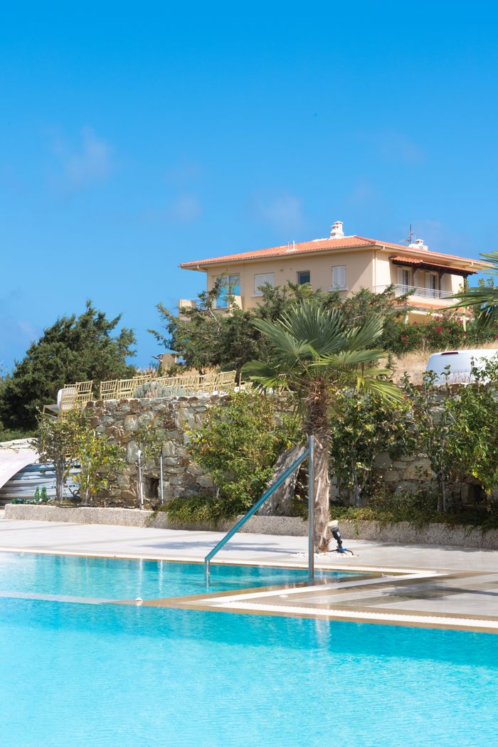 Elegant villa with a pool and palm trees under a bright blue sky.